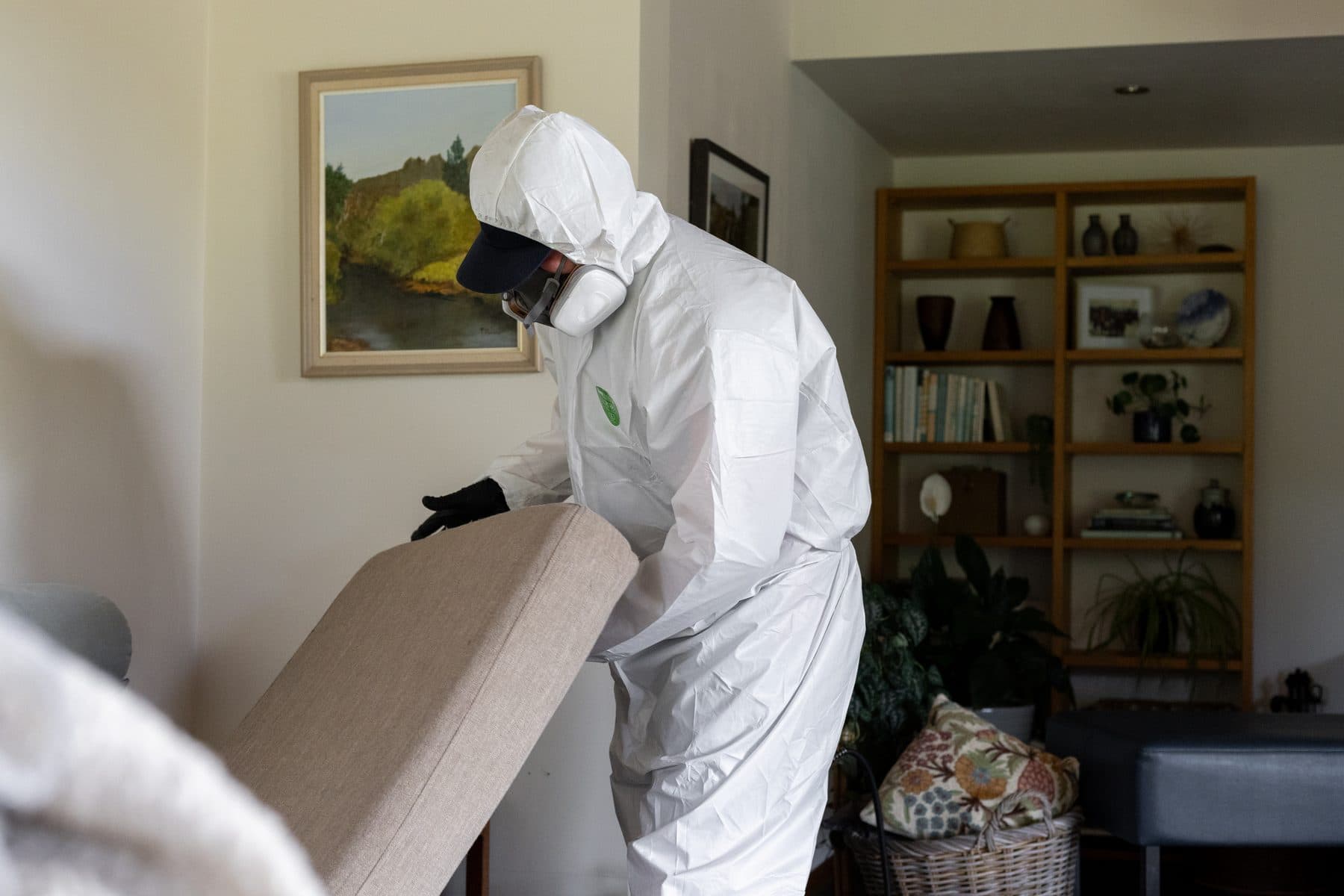 A pest control technician inspecting under a cabinet with a flashlight