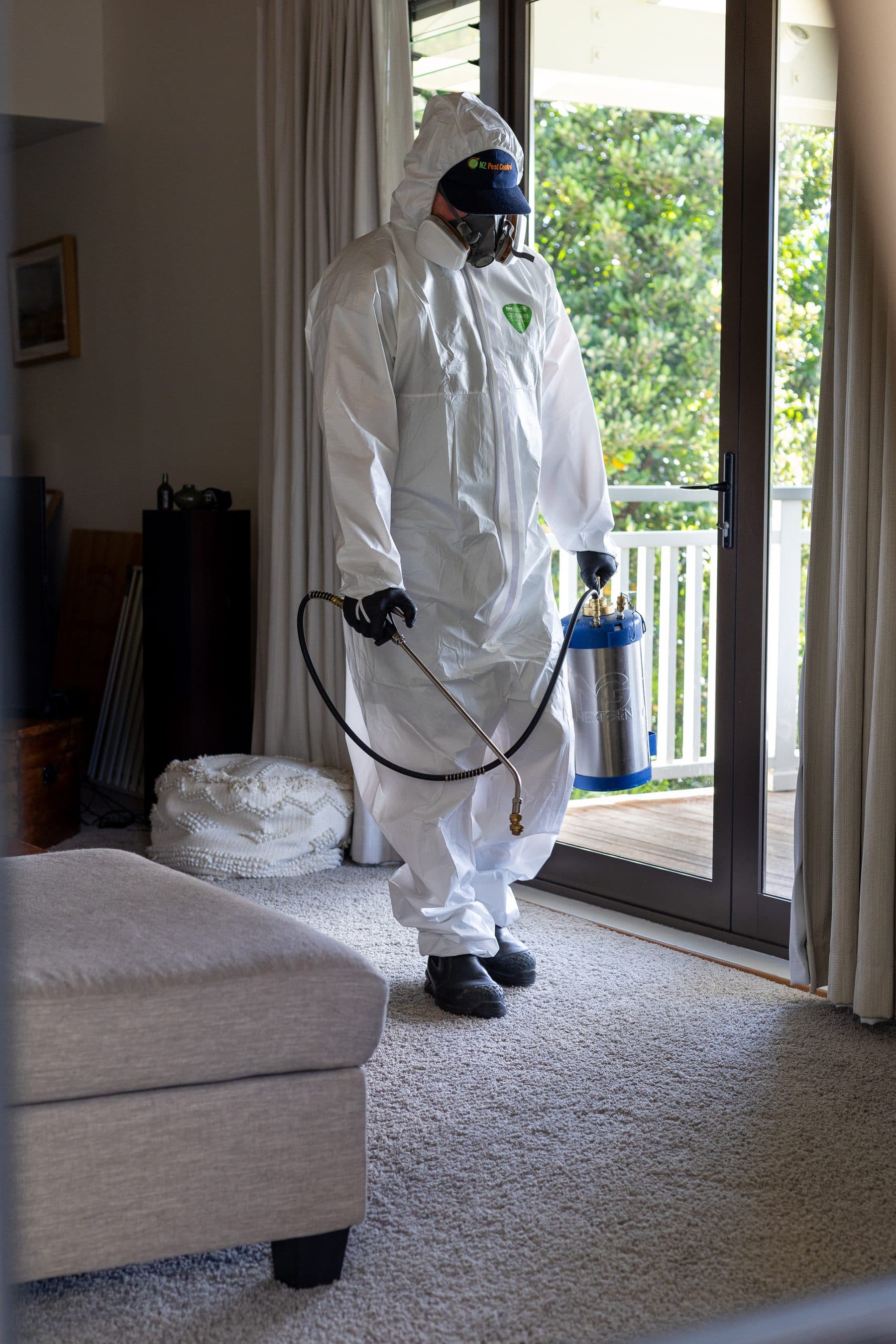 A technician in protective equipment treating inside a home